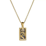 A gold rectangular tarot card pendant labeled THE MAGICIAN, featuring a black enamel background, a gold hand reaching up to a sunburst with blue stones, and a cloud motif.