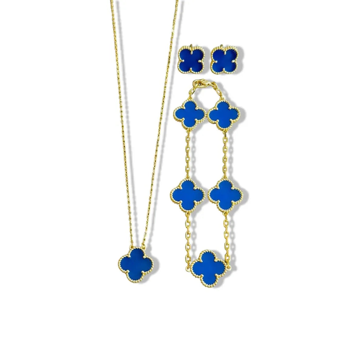 An elegant 18K gold plated jewelry set featuring a black four-leaf clover necklace, matching bracelet, and stud earrings laid on a white background.