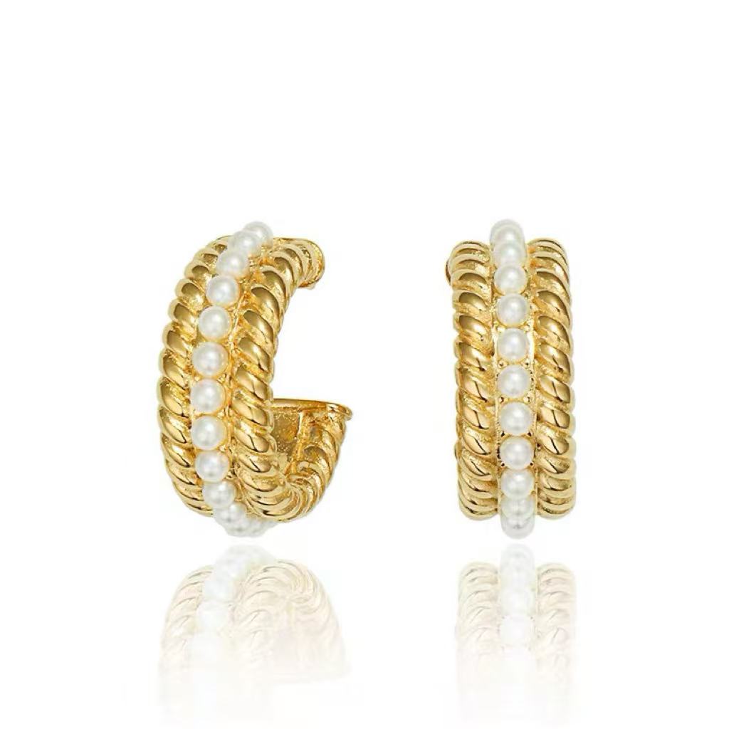 Studio product photography of a pair of gold braided croissant hoops with a center row of pearls, isolated on a white background.