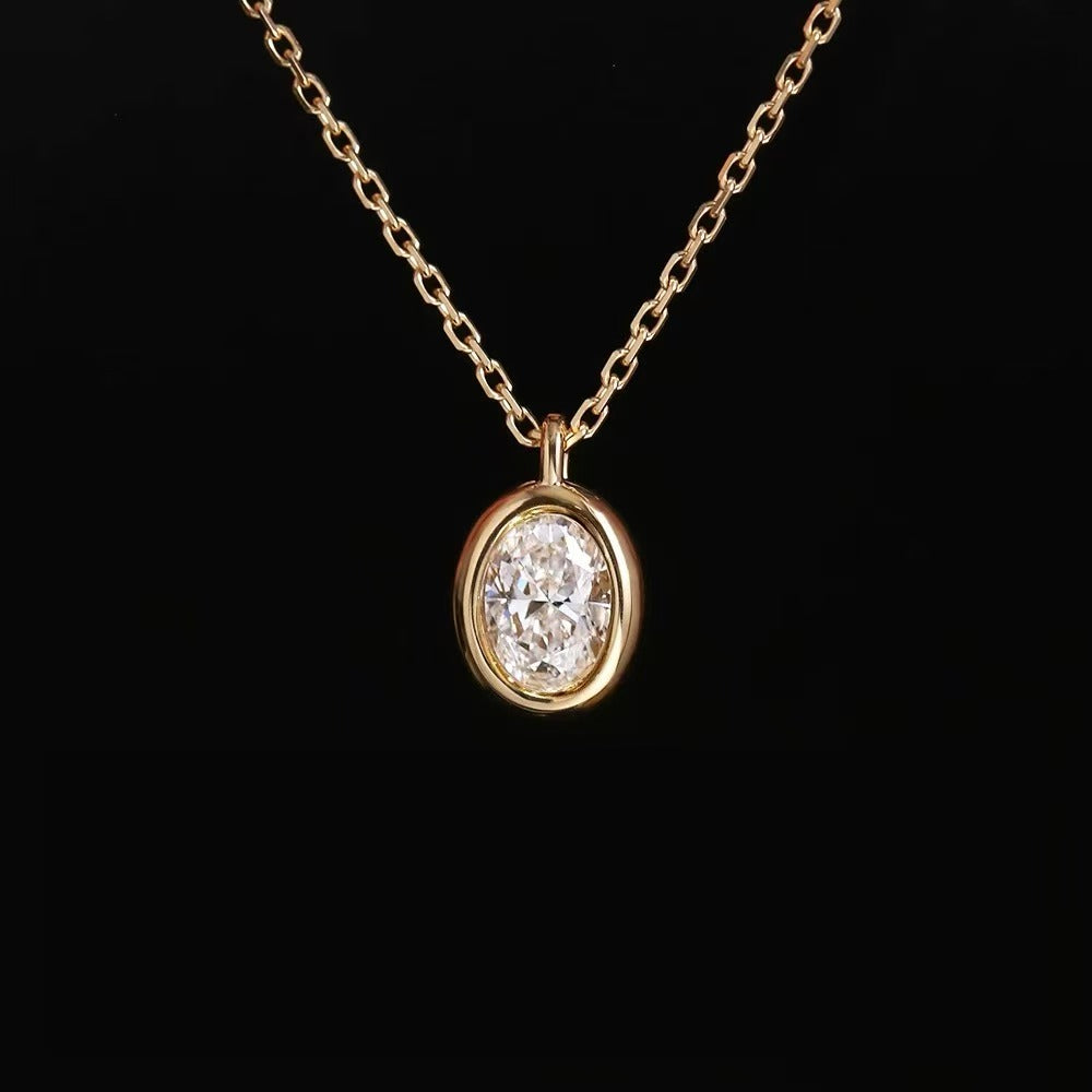 A striking close-up of the Bubble Luxe oval lab diamond necklace in a thick 18K gold bezel setting against a black background.