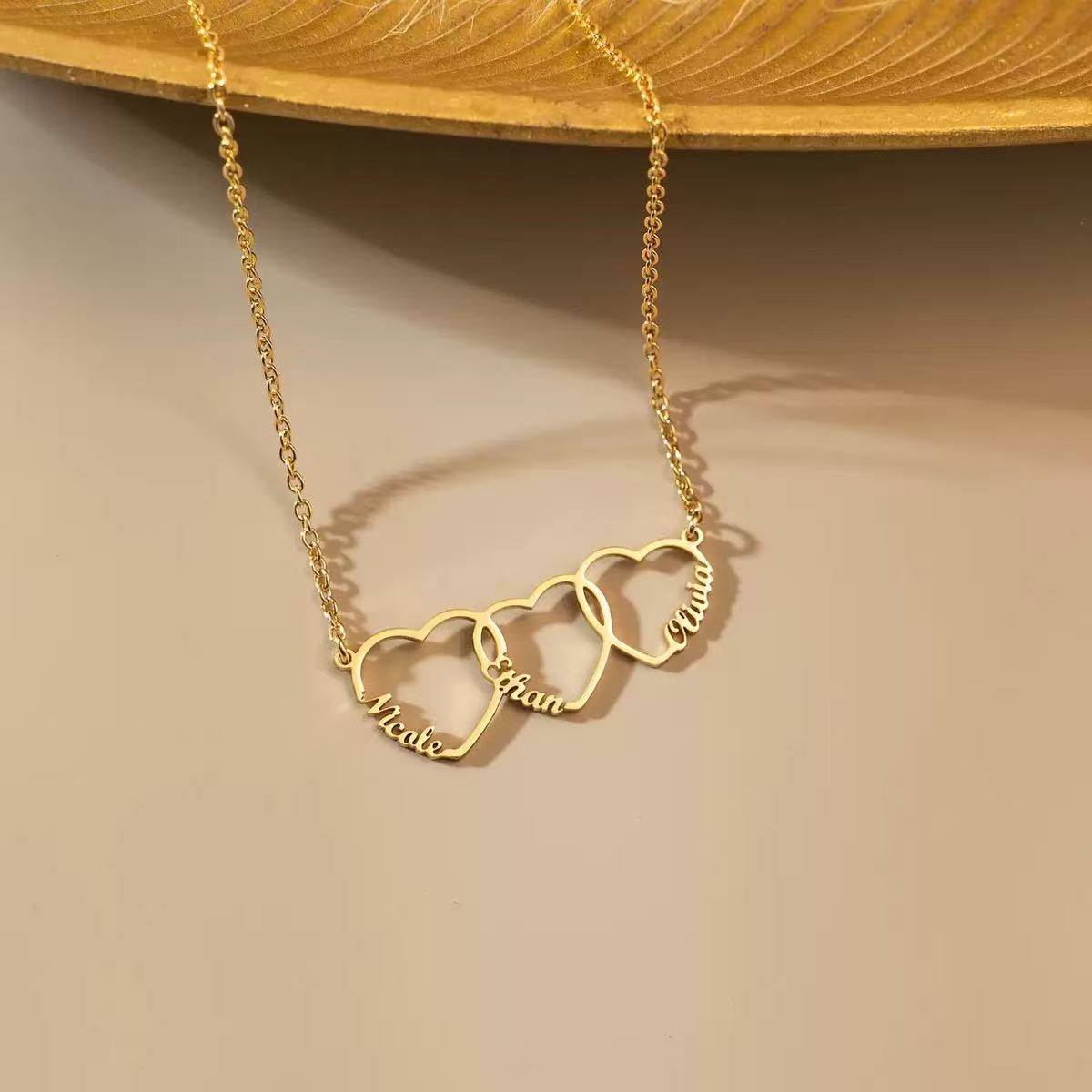 Close-up of the personalized heart necklace held in hands, showcasing the delicate script engraving and fine chain.