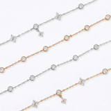 A collection of dainty clover charm bracelets in 14K rose gold plated and 925 sterling silver laid diagonally on a white surface.