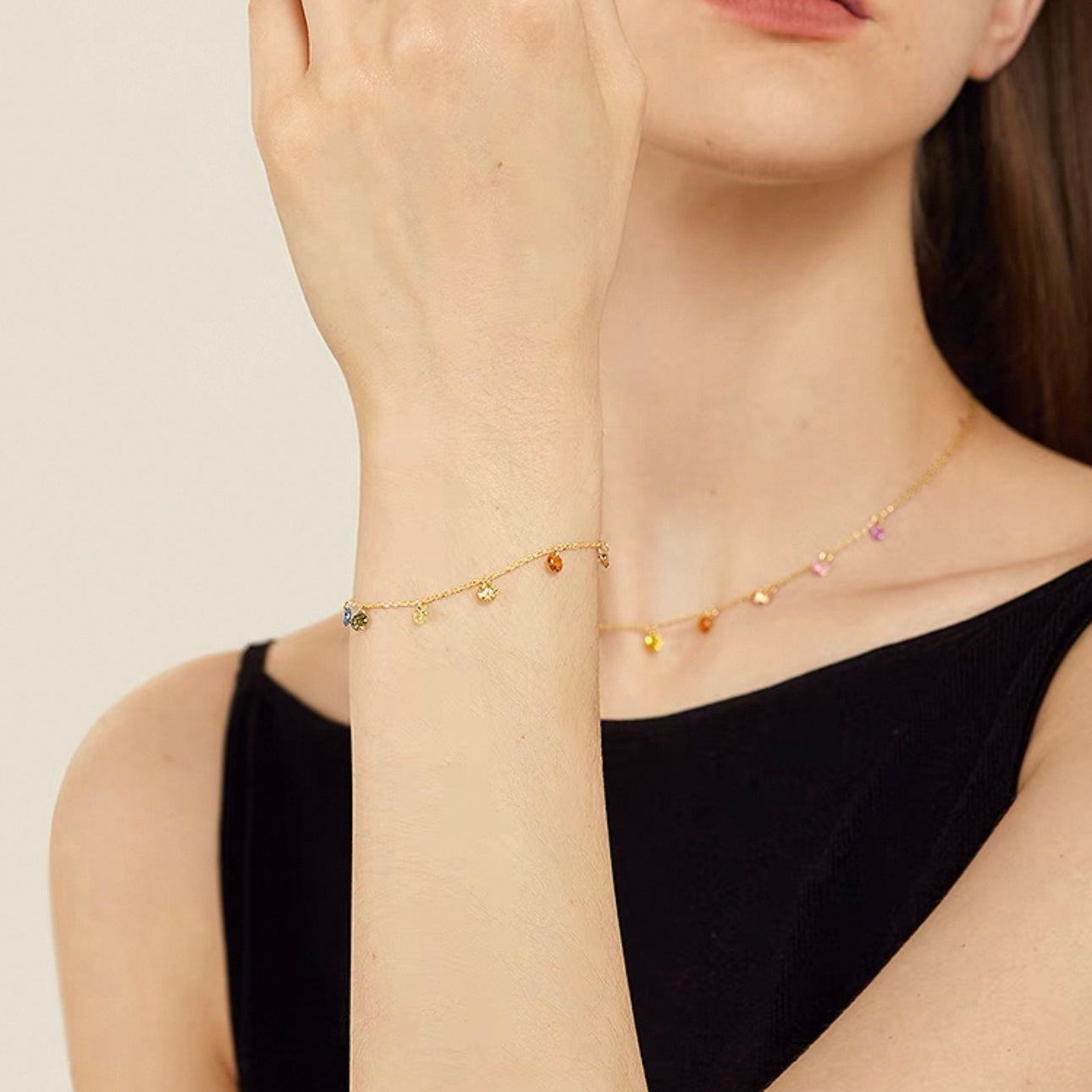 Detailed shot of the delicate 18K gold plated colorful gemstone bracelet on a model's wrist.