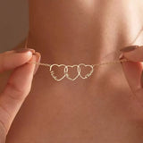 A model wearing the Custom Heart Stack necklace featuring three interlocking hearts engraved with names in 18K gold.