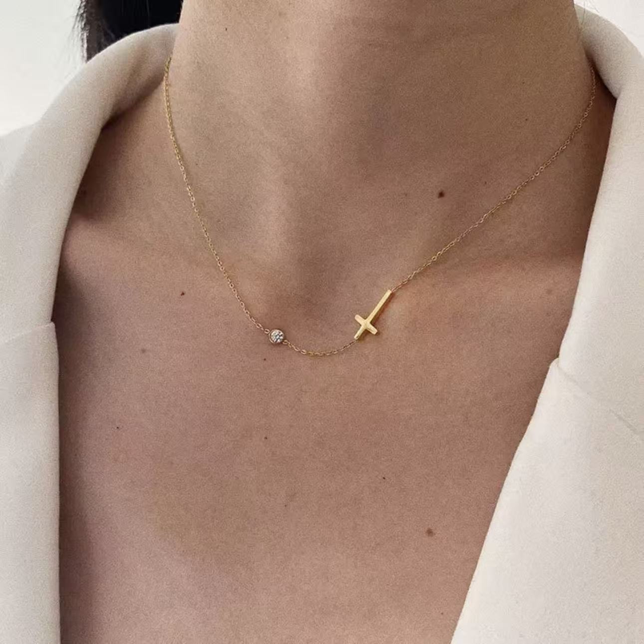 Close-up of the dainty sideways cross and cubic zirconia necklace resting beautifully on a woman's collarbone.