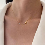 Close-up of the dainty sideways cross and cubic zirconia necklace resting beautifully on a woman's collarbone.
