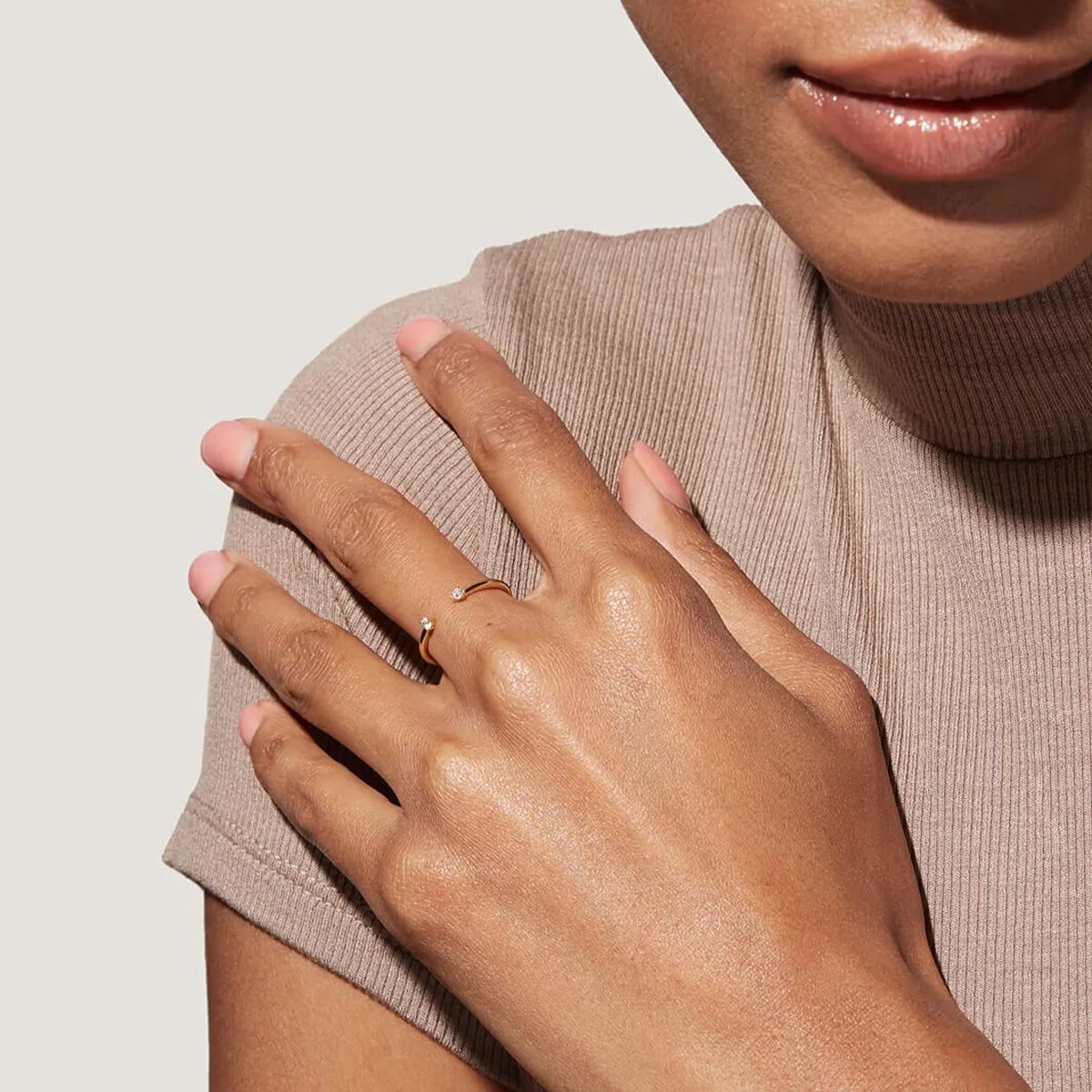 A stylish model wearing a dainty gold gap ring on her index finger, showcasing a modern jewelry aesthetic.