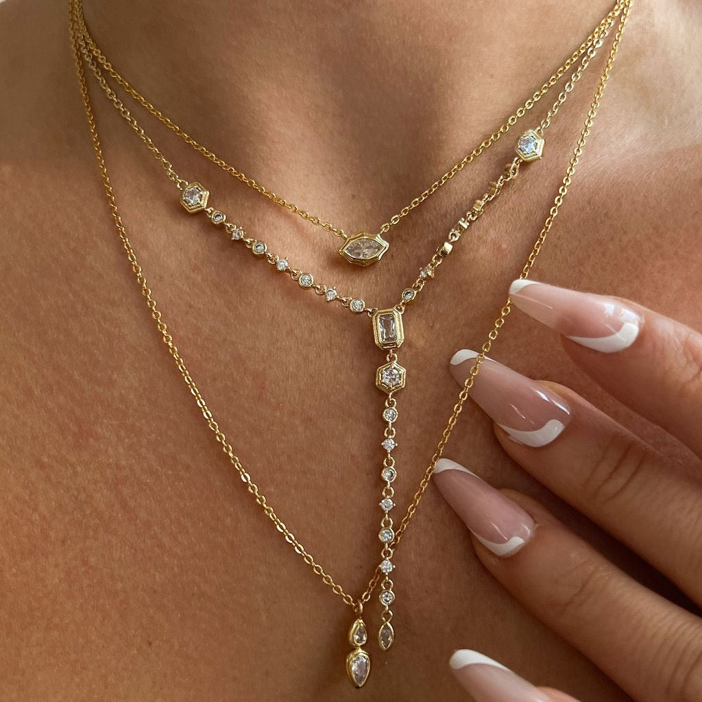 Detailed flat lay of the dainty gold gemstone necklaces resting on a textured stone surface.