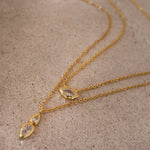 Detailed flat lay of the dainty gold gemstone necklaces resting on a textured stone surface.