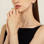 Close-up of the dainty rainbow cubic zirconia necklace resting on a model's collarbone.
