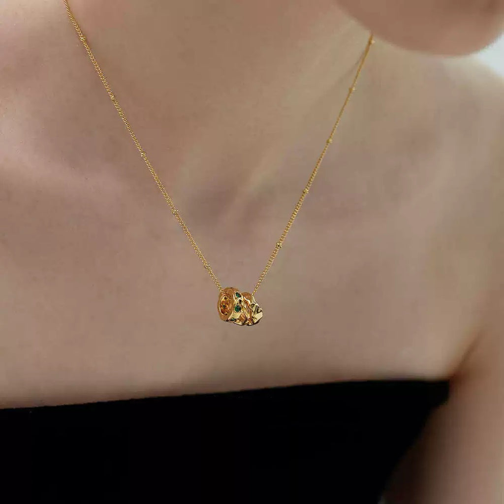 A delicate 18K gold-plated necklace with a three-ring emerald pendant resting beautifully on a model's collarbone.