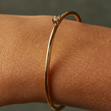 Close-up detail of a single brilliant-cut cubic zirconia stone set on a delicate 18K gold-plated open cuff bangle, highlighting the craftsmanship.