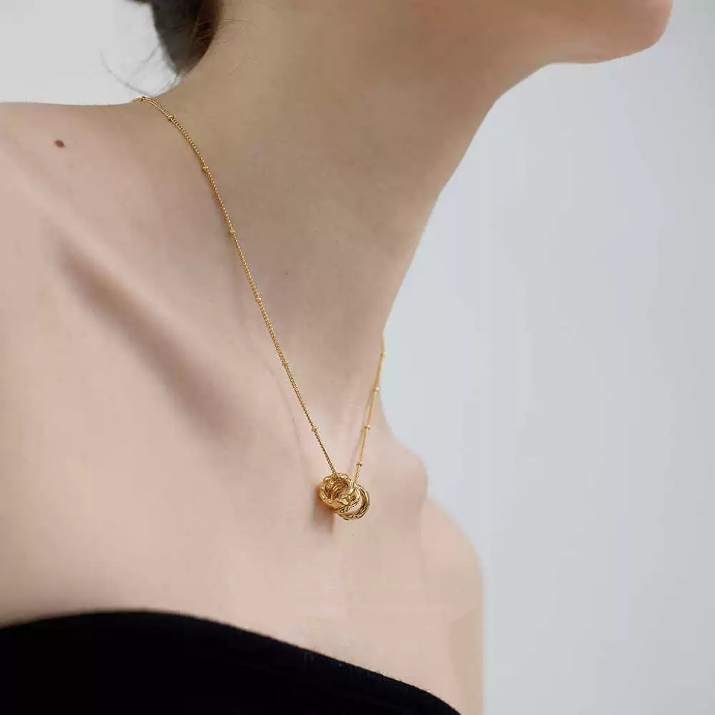Close-up detail of the Emerald Trio Ring Necklace on a model, showcasing the rich green stones and hand-hammered gold textures.