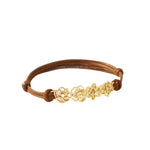 A custom gold birth flower bracelet featuring four distinct month flower charms strung on an adjustable brown waxed cotton cord.