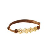 A custom gold birth flower bracelet featuring four distinct month flower charms strung on an adjustable brown waxed cotton cord.