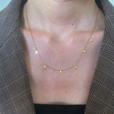 A woman wearing the dainty 18K gold plated Glisten Gemstone Necklace featuring subtle crystal charms.
