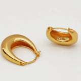 Two gold-plated horseshoe-shaped hoop earrings lying flat on a white surface.