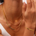 Detailed view of a gold-plated snake chain bracelet on a model’s wrist, emphasizing its elegant shimmer.