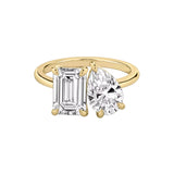 Studio shot of the yellow gold plated Toi et Moi ring featuring pear and emerald cut stones on a white background.