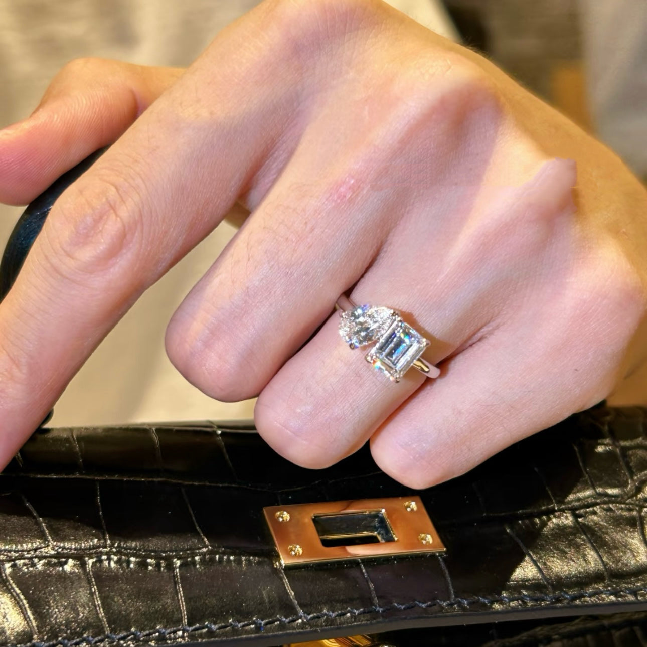 A woman's hand holding a black leather bag, wearing the elegant S925 silver Toi et Moi two-stone ring.