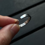Close-up of the inner band of a silver ring revealing the hidden engraved message "save me".