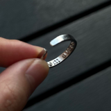 Close-up of the inner band of a silver ring revealing the hidden engraved message "save me".