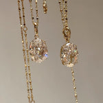 Front view of two dazzling 10 carat oval high-carbon diamond necklaces hanging side by side, reflecting pure light.