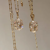 Front view of two dazzling 10 carat oval high-carbon diamond necklaces hanging side by side, reflecting pure light.