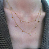 Close-up of two layered Glisten Gemstone Necklaces, showcasing the baguette, triangle, and teardrop stones.