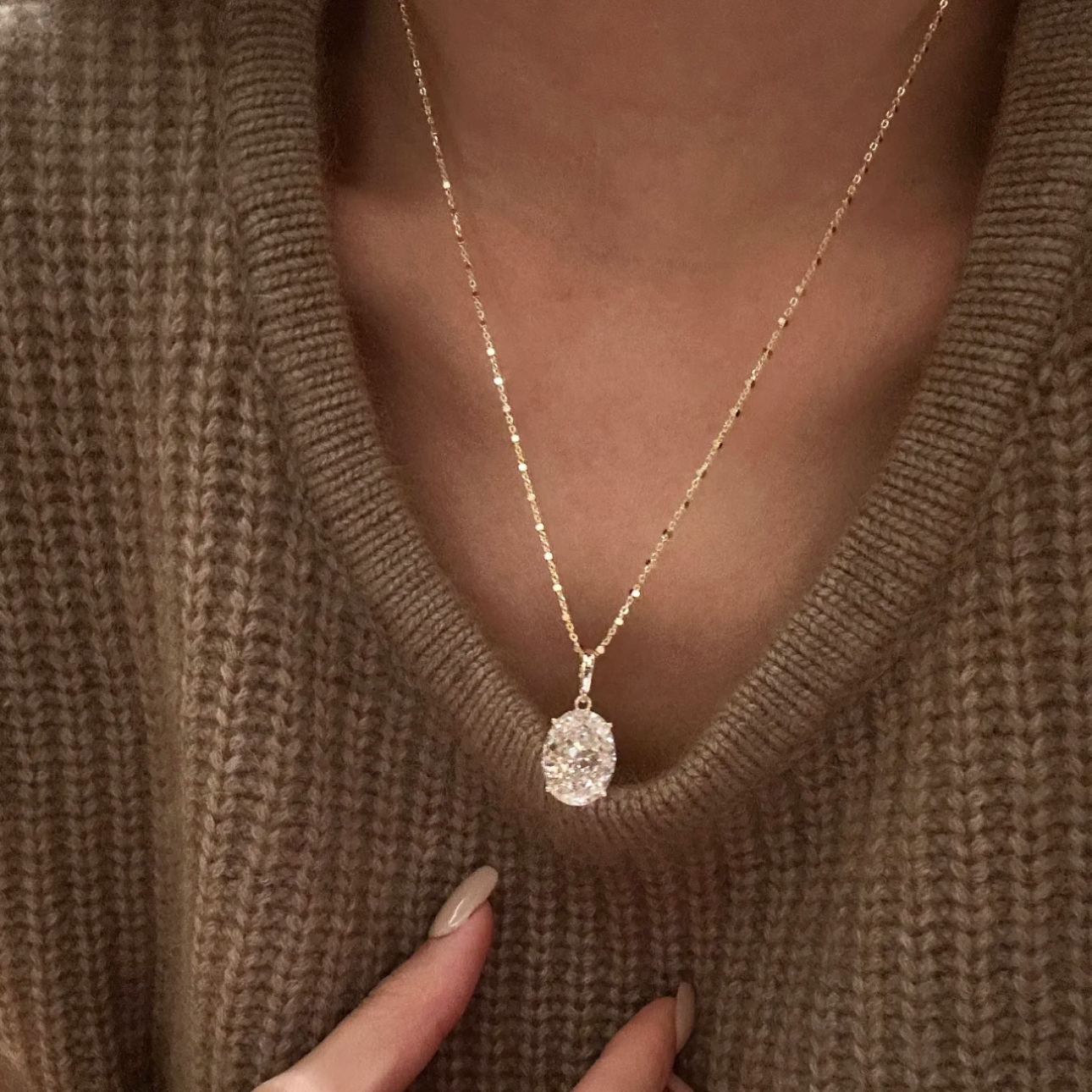 A model wearing a warm brown knit sweater showcasing the stunning 10 carat oval rose gold pendant necklace.