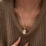 A model wearing a warm brown knit sweater showcasing the stunning 10 carat oval rose gold pendant necklace.