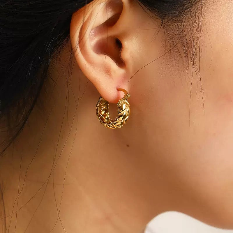 Side view of a woman wearing the gold quilted hoop earrings, highlighting the elegant textured lattice design.