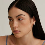 A stylish model with freckles wearing a delicate 925 silver 3-stone huggie hoop earring, showcasing an effortless everyday look.