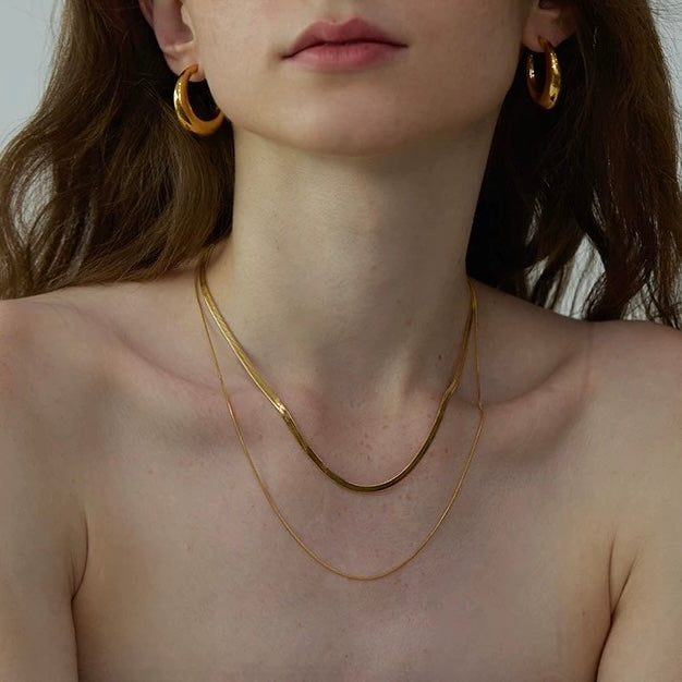 Close-up of the liquid metal shine on the layered gold Snake Chain Duo Necklace draped gracefully over the collarbone