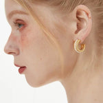 Macro view of a braided gold chunky hoop on an ear, showing the high-luster faux pearls nestled in the twisted gold design.
