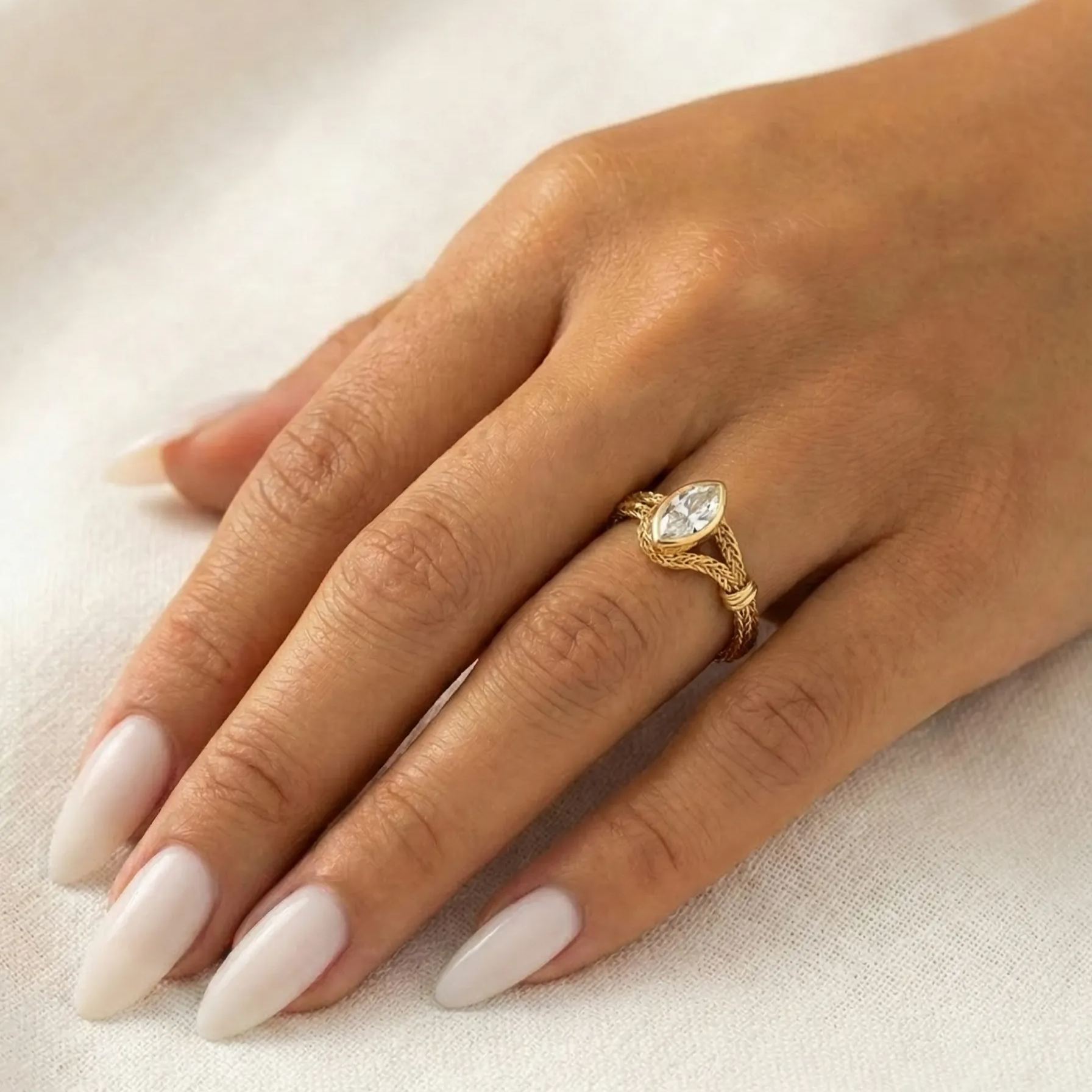 A model wearing the 18K solid gold flexible wrap ring, showcasing the 1-carat marquise lab diamond and unique woven chain design on the finger.