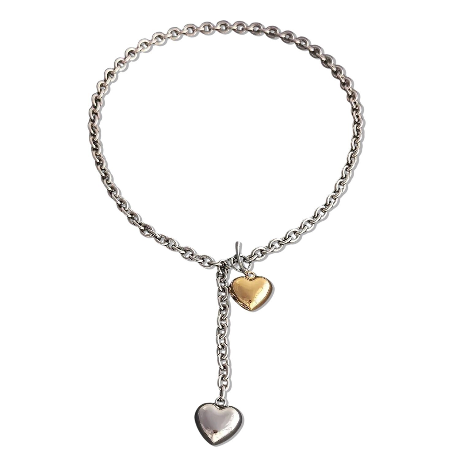 A mixed metal lariat necklace with a chunky silver chain, front toggle clasp, and two dangling puffy hearts in silver and gold, isolated on a white background.