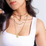 Close-up of a model in a white tank top showcasing the layered aesthetic with the multicolor rainbow cubic zirconia station necklace.