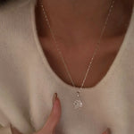A woman in a cozy white sweater wearing the breathtaking 10 carat oval silver pendant necklace on her collarbone.