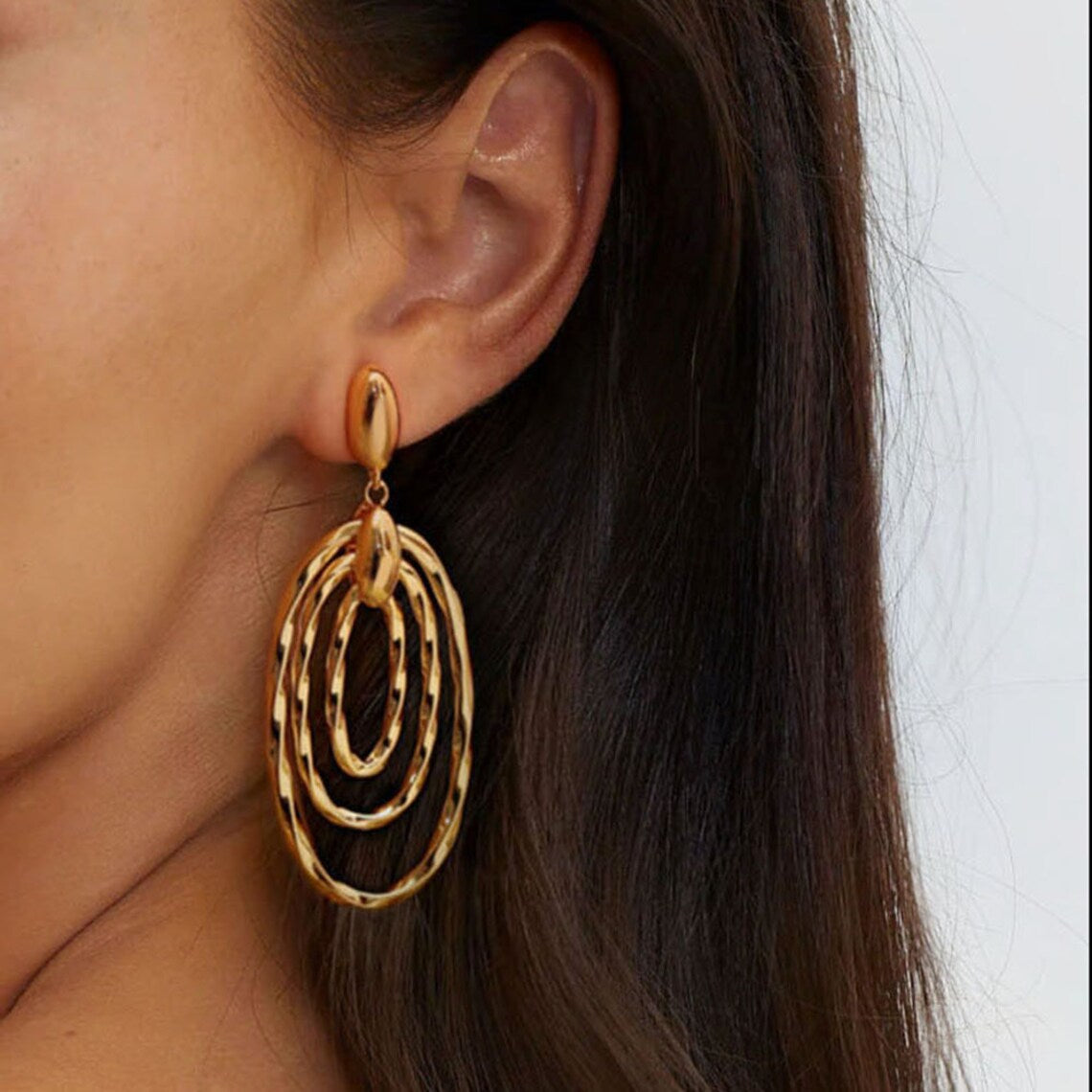 Close-up of a woman wearing 18K gold vintage-inspired textured oval drop earrings, showcasing their lightweight statement design.