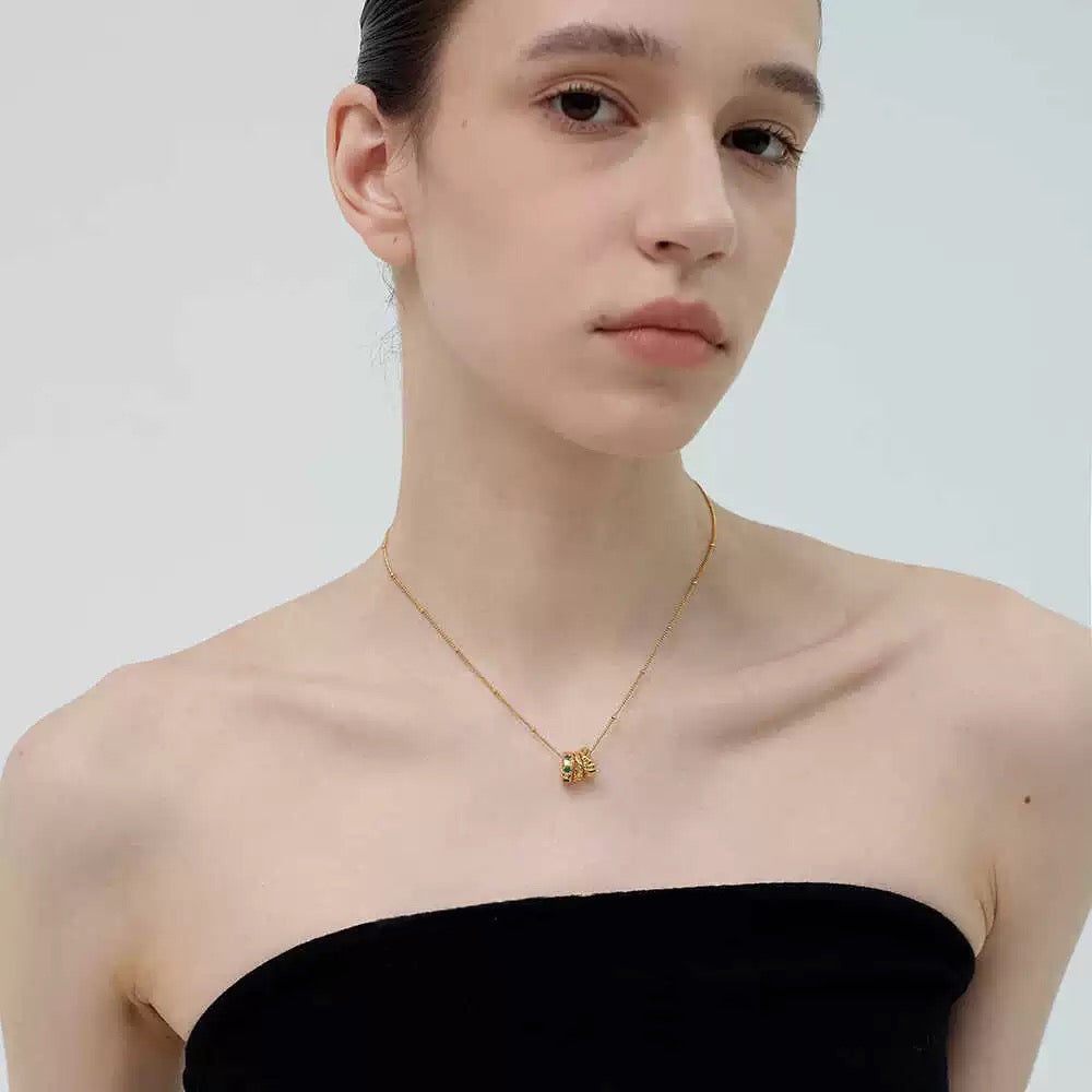 A stylish model wearing a black tube top and the 18K gold-plated Emerald Trio Ring Necklace, highlighting its delicate drape.