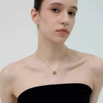 A stylish model wearing a black tube top and the 18K gold-plated Emerald Trio Ring Necklace, highlighting its delicate drape.