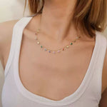 Close-up of a woman's neck wearing the delicate rainbow dangle station necklace in gold-plated sterling silver.