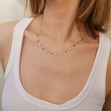 Close-up of a woman's neck wearing the delicate rainbow dangle station necklace in gold-plated sterling silver.