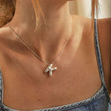 A woman wearing a high polish 925 sterling silver 3D puff initial letter K necklace on a delicate bean chain, styled with a blue denim top.