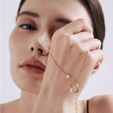Close-up of a woman wearing a 14K gold plated vintage initial necklace with a rectangular sunburst frame and an asymmetrical freshwater pearl.