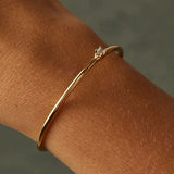 A natural view of a dainty gold open cuff bracelet on a person's wrist, emphasizing its subtle elegance and fit.