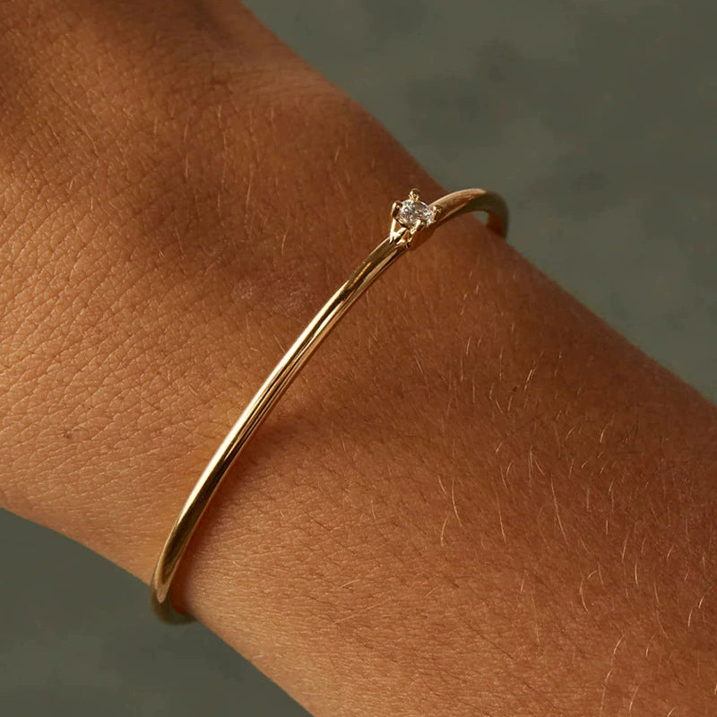 A natural view of a dainty gold open cuff bracelet on a person's wrist, emphasizing its subtle elegance and fit.