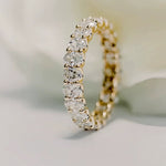 A close-up of the 18K gold Oval Lab Diamond Eternity Band standing upright against a soft white background, showcasing its uninterrupted sparkle.
