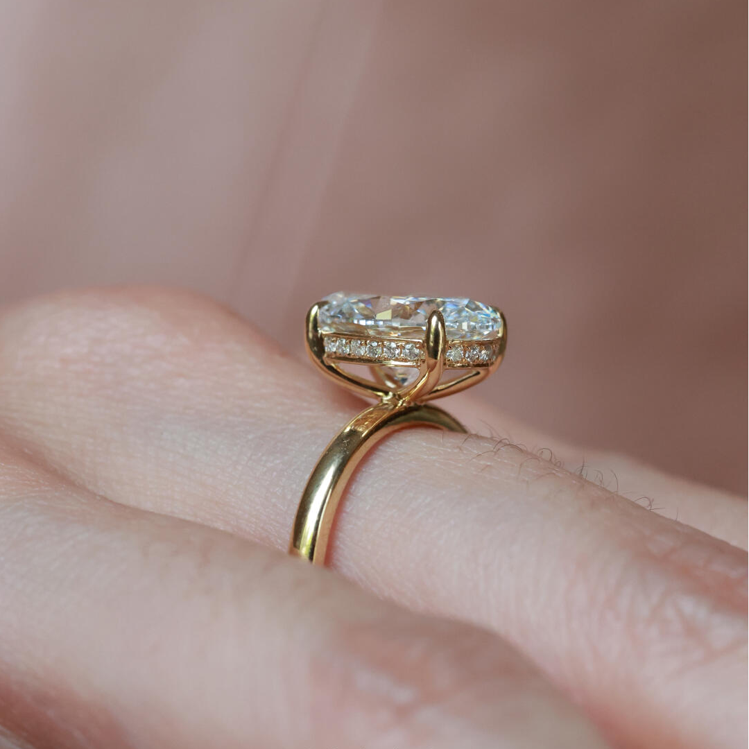 A model wearing the 3 ct oval ice-flower cut solitaire ring with an aesthetic, modern-heirloom stacking band against a textured backdrop.